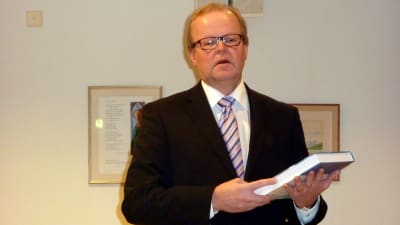 Vasa sjukvårdsdistrikts fullmäktigeordförande Gösta Willman tar emot sitt exemplar av centralsjukhushistoriken.