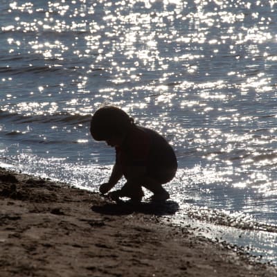 Ett barn leker vid vattnet på Sandudds badstrand i Helsingfors