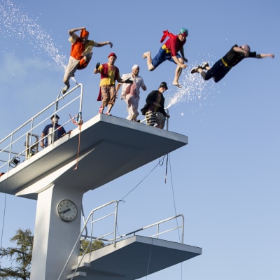 Clownhoppare hoppar ner från hopptorn på Simstadion.
