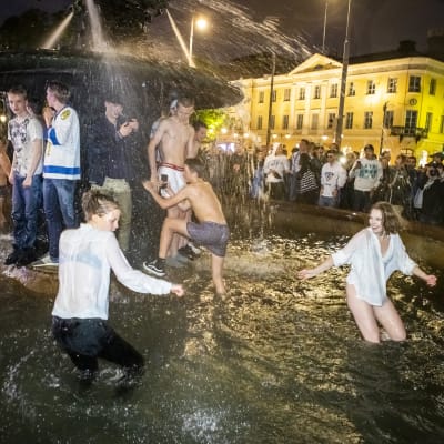 Flertal personer i våta kläder dansar i bassängen där Havis Amanda statyn står. 