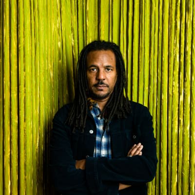Colson Whitehead nojaa kullanväriseen verhoon.