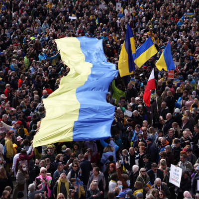 Ihmismeri kannattelee valtavan kokoista Ukrainan lippua Senaatintorilla.