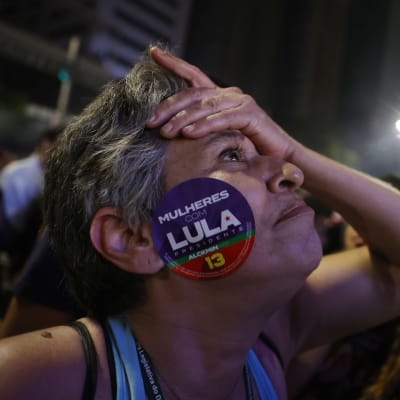 Den tidigare presidenten Lulas anhängare i São Paulo ser nervös ut med en hand i pannan och med ett stort klistermärke på kinden.