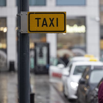Taksit jonottavat asiakkaita Pasilan asemalla Helsingissä. Lähikuvassa taxi-kyltti.