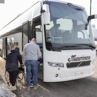 Bussikuljettaja auttaa liikuntavammaista Ukrainan pakolaista bussiin.