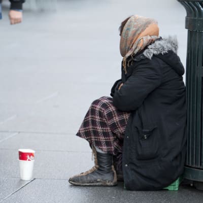 Tiggande kvinna som sitter på huk på gatan. 