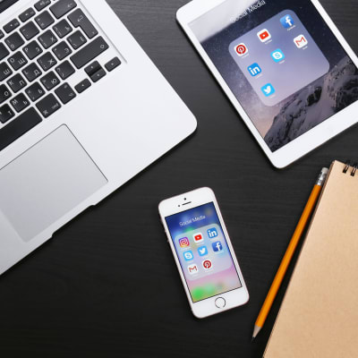 En iPhone, iPad och Macbook på ett bord.