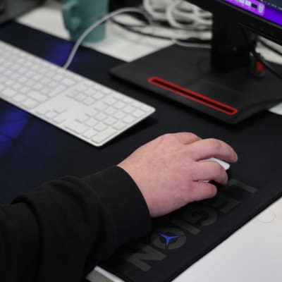 Mies pitää kättään tietokoneen hiiren päällä.