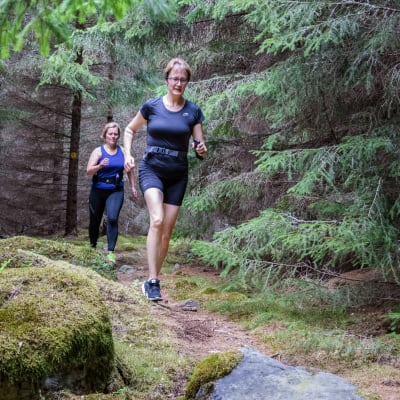 Kaksi naista juoksee metsäpolulla