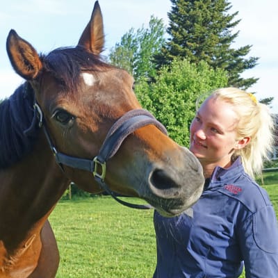 Ryttaren Patricia Westman står ute på en grön äng med hästen Hip.