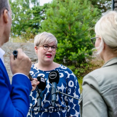 Annika Saarikko i Marimekko-känning omgiven av reportrar.