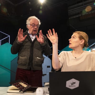 Toimittaja Matti Rönkä ja toimittaja Piia Pasanen keskustelemassa intensiivisesti Yleisradion vaalilähetyksen lavasteissa 1.4.2023