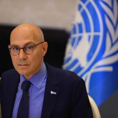 FN:s högkommissarie för mänskliga rättigheter Volker Türk med en mikrofon framför sig och FN-flaggan bakom sig.