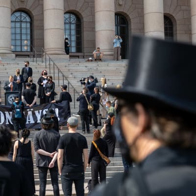 Människor klädda i svart utanför riksdagshuset i samband med en demonstration.