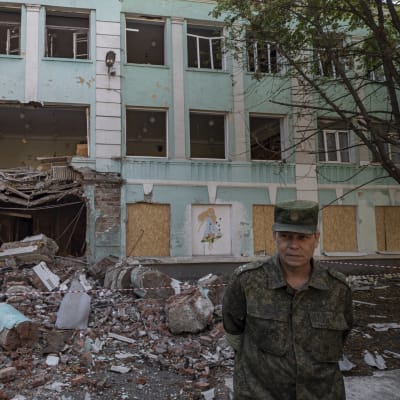 En bombhärjad byggnad, som en soldat står framför.