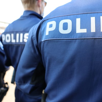 Ryggarna på poliser där det på finska står poliisi.