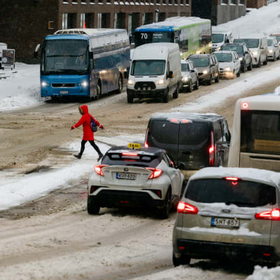 Autoja tiellä lumisessa kaupungissa.