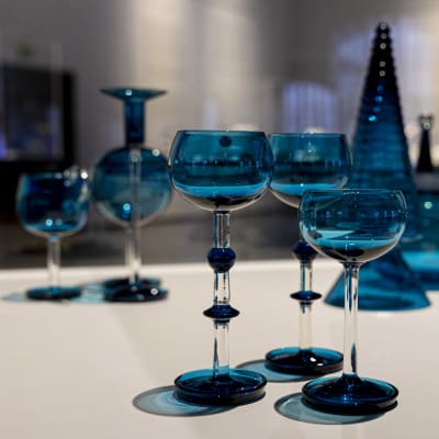 Nanny Stillin suunnittelemia sinisä Harlekiini-sarjan lasiesineitä. Etualalla kolme jalallista lasia.