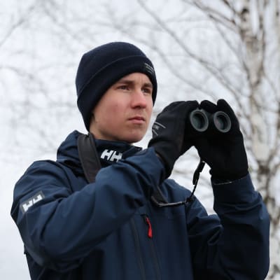 Lintuharrastaja Elias Kaasinen on nostamassa kiikareita silmilleen. 