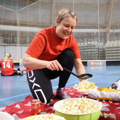 Riikka Turunen laittaa popcornia lautaselle salibandykentällä.