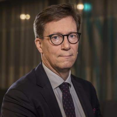 Mikko Pietilä, en man med glasögon, blå kavaj och slips, tittar in i kameran.