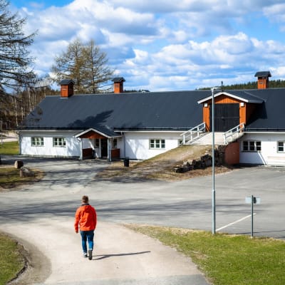 En ung man går mot en byggnad