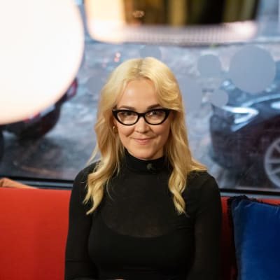 En kvinna tittar in i kameran och ler.