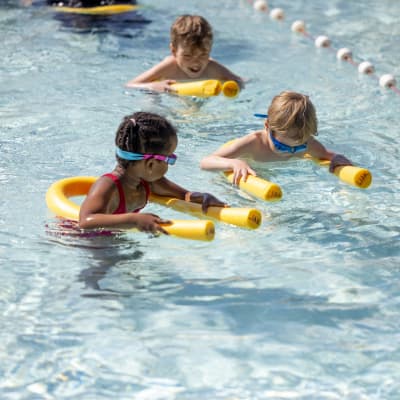 Barn med simkuddar i en simbassäng. 