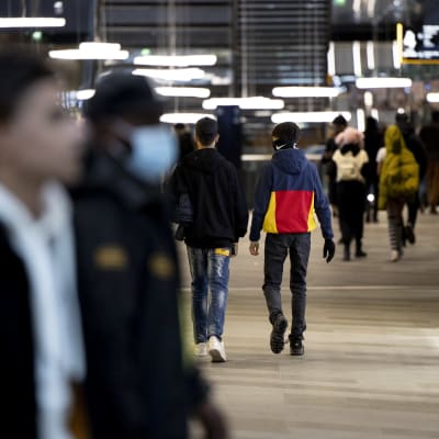 Flera mörkklädda ungdomar hänger ihop i ett köpcentrum.