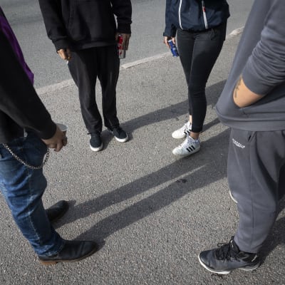 neljä anonyymiä opiskelijaa seisovat ulkona ringissä