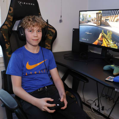 14-vuotias tietokonepeliharrastaja Tomas Julkunen istuu huoneensa pelituolissa.