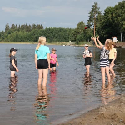 Neljäsluokkalaisia leikkii pallolla rantavedessä Joensuussa kesäpäivänä.