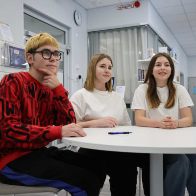 Kolme venäläistä lukionuorta, poika ja kaksi tyttöä, istuvat pöydän ääressä Tohmajärven kirjastossa.