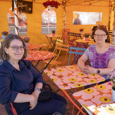 Helsinkiläinen Kaija Blom ja keravalainen Liisa Sahi istuskelevat kahvilassa Helsingin kauppatorilla.
