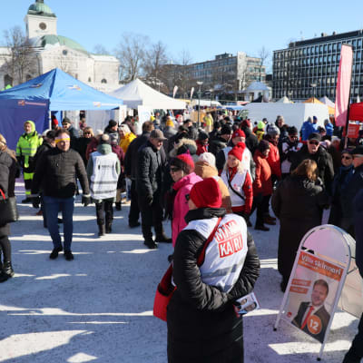 Ihmisiä Hämeenlinnan torilla tutustumassa eduskuntavaali ehdokkaisiin.