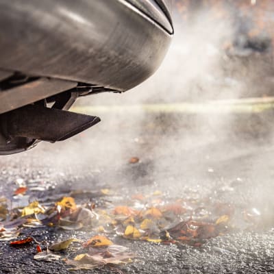 auto ja pakokaasua syksyisessä maisemassa