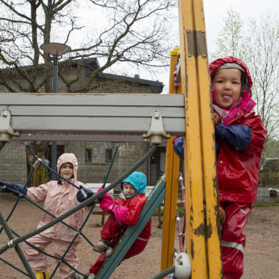 Dagisbarn klättrar i lekställningar på en dagisgård. 