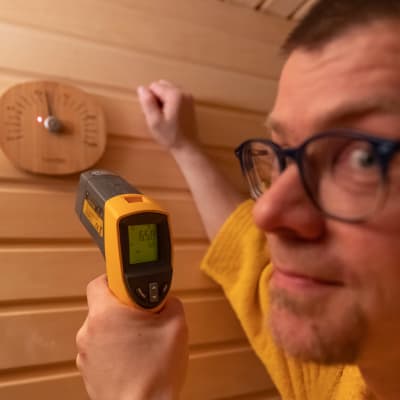 Saunologi Lassi A.Liikanen mittaa saunan lämpötilaa.