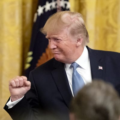 Trump med knuten näve, vänd til höger i talarstolen.