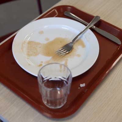 En tom tallrik på en bricka efter att någon ätit i en skolmatsal