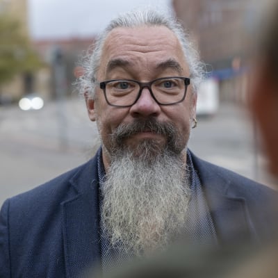 Närbild på en man i kavaj. I bakgrunden syns suddig trafik.