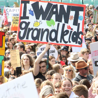 En klimataktivist håller upp ett plakat med texten "I wan't grandkids".