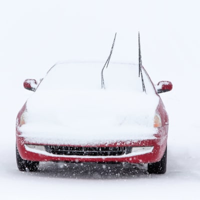 Bil intäckt i snö.