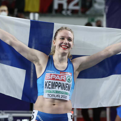 Lotta Kemppinen poseeraa Suomen lipun kanssa.