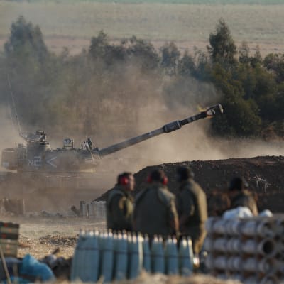 Bild på en tanker som står vid gränsen till Gaza. Bredvid står soldater från den israeliska militären IDF.