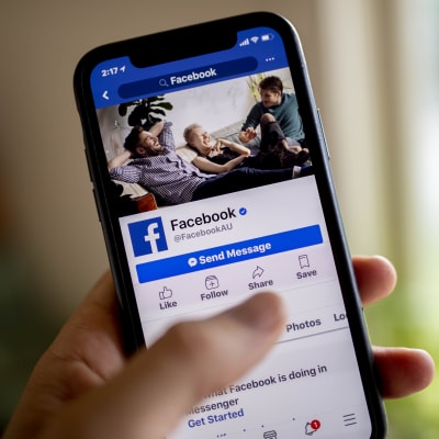 En person håller i en telefon, hen är inne på appen Facebook.