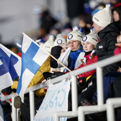 Mennalan perhe seuraa hiihtoa Olympiastadionin katsomossa.