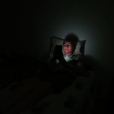 Liinu Lavikainen selaa puhelinta sängyssä.