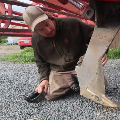Anders Abrahamsson på knä, han synar traktorplogen som drog av elkabeln.