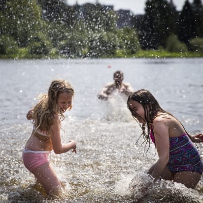 Två barn i simkläder leker i en sjö
